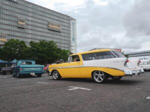 Vintage Chevrolet cars showcased at an outdoor meetup in a city parking lot.