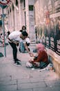A man giving to a homeless woman on an Istanbul street, capturing urban generosity.