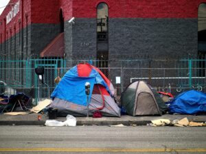 A view of tents set up on a sidewalk in Los Angeles, representing urban homelessness.