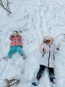 Two children enjoying winter fun, lying in the snow in Etimesgut, Ankara.